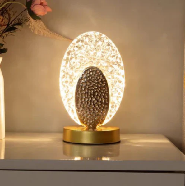 Tischlampe mit ovalem Leuchtrahmen in Kristalloptik und gehämmertem Mittelteil für Nachttisch und Kommode – runder Fuß in Gold, warmweißes Licht